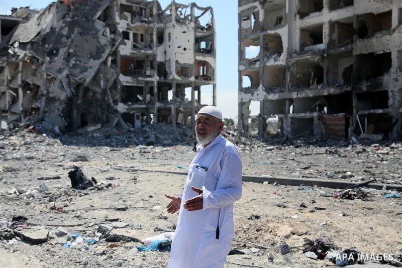 Palestinians walk in front of the rubble of buildings destroyed in Israeli strikes, in Beit Lahiya, northern Gaza Strip, Monday, Aug. 4, 2014.. Photo by Ezz al-Zanoun