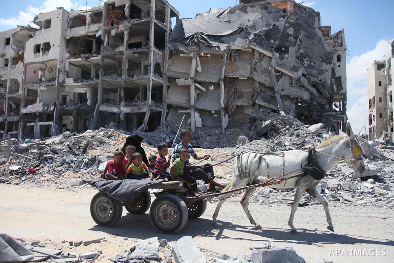 Palestinians walk in front of the rubble of buildings destroyed in Israeli strikes, in Beit Lahiya, northern Gaza Strip, Monday, Aug. 4, 2014.. Photo by Ezz al-Zanoun
