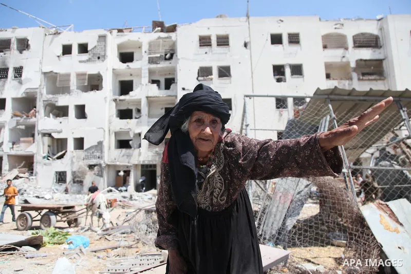 Palestinians walk in front of the rubble of buildings destroyed in Israeli strikes, in Beit Lahiya, northern Gaza Strip, Monday, Aug. 4, 2014.. Photo by Ezz al-Zanoun