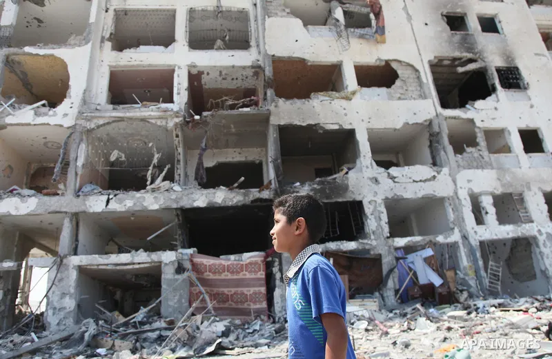 Palestinians walk in front of the rubble of buildings destroyed in Israeli strikes, in Beit Lahiya, northern Gaza Strip, Monday, Aug. 4, 2014.. Photo by Ezz al-Zanoun