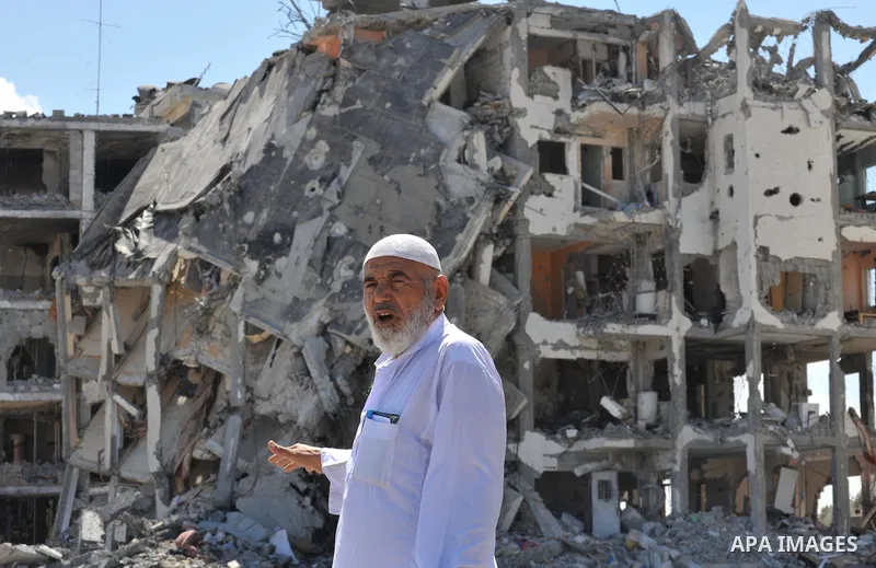 Palestinians walk in front of the rubble of buildings destroyed in Israeli strikes, in Beit Lahiya, northern Gaza Strip, Monday, Aug. 4, 2014.. Photo by Ezz al-Zanoun