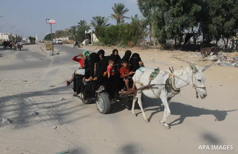 Members of a Palestinian family ride in a donkey cart as they return to their house in Beit Lahiya town, which witnesses said was heavily hit by Israeli shelling and air strikes during the Israeli offensive, in the north...
