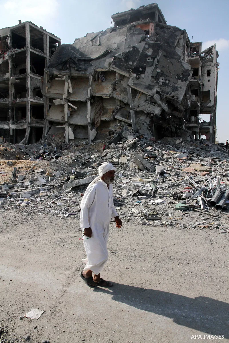A Palestinian carries his belonging A Palestinian man walks past destroyed buildings as he walks past a badly damaged residential building after returning to Beit Lahiya town, which witnesses said was heavily hit by Isra...