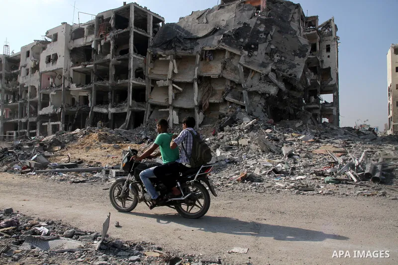 Palestinian men ride a Motorcycle past destroyed and badly damaged residential buildings as they return to Beit Lahiya town, which witnesses said was heavily hit by Israeli shelling and air strikes during the Israeli off...