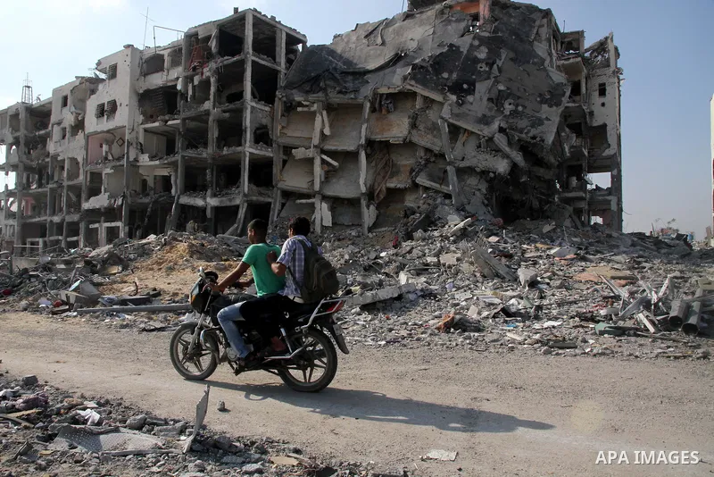 Palestinian men ride a Motorcycle past destroyed and badly damaged residential buildings as they return to Beit Lahiya town, which witnesses said was heavily hit by Israeli shelling and air strikes during the Israeli off...