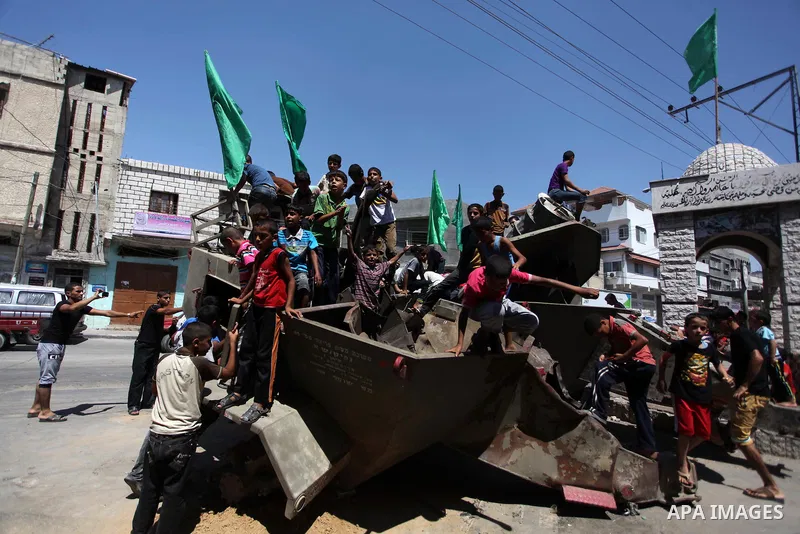 Palestinian children play on the remains of a destroyed Israeli military vehicle, in the east of Khan Younis in the southern Gaza Strip August 5, 2014. Israel pulled its ground forces out of the Gaza Strip on Tuesday and...