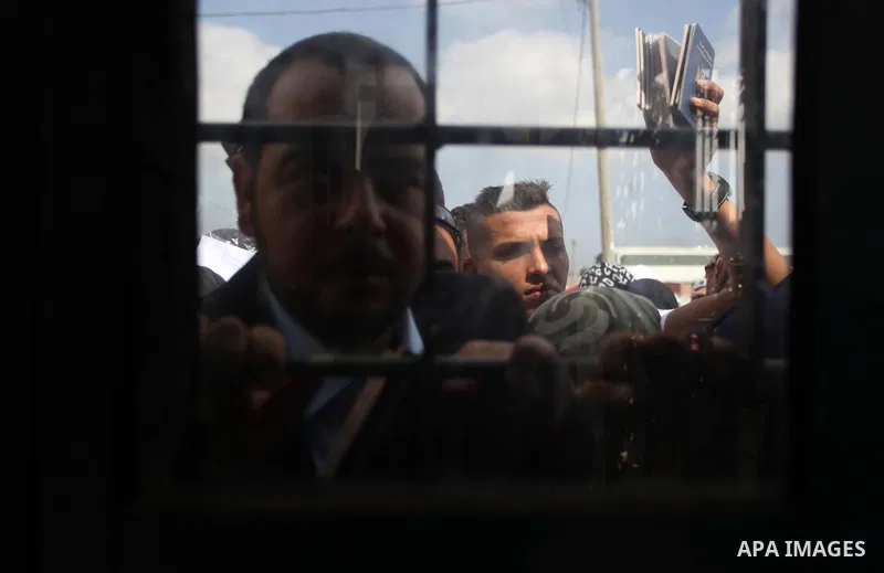 People, hoping to cross into Egypt, stand behind a gate as they wait at the Rafah crossing between Egypt and the southern Gaza Strip August 5, 2014. Israel pulled its ground forces out of the Gaza Strip on Tuesday and be...