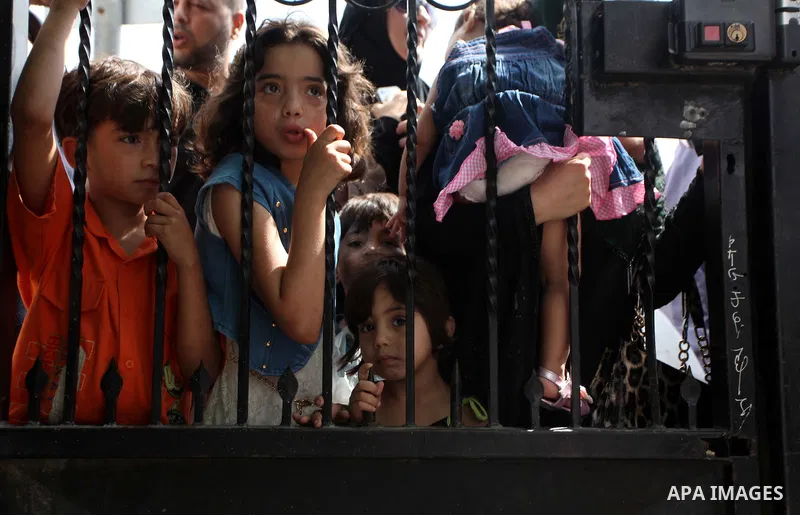 People, hoping to cross into Egypt, stand behind a gate as they wait at the Rafah crossing between Egypt and the southern Gaza Strip August 5, 2014. Israel pulled its ground forces out of the Gaza Strip on Tuesday and be...