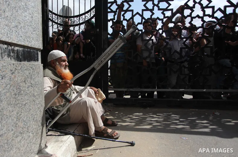 People, hoping to cross into Egypt, stand behind a gate as they wait at the Rafah crossing between Egypt and the southern Gaza Strip August 5, 2014. Israel pulled its ground forces out of the Gaza Strip on Tuesday and be...