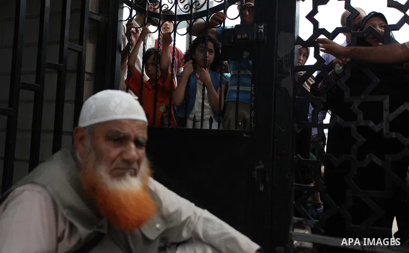 People, hoping to cross into Egypt, stand behind a gate as they wait at the Rafah crossing between Egypt and the southern Gaza Strip August 5, 2014. Israel pulled its ground forces out of the Gaza Strip on Tuesday and be...