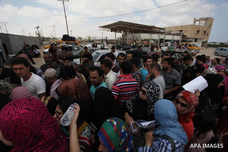 People, hoping to cross into Egypt, stand behind a gate as they wait at the Rafah crossing between Egypt and the southern Gaza Strip August 5, 2014. Israel pulled its ground forces out of the Gaza Strip on Tuesday and be...