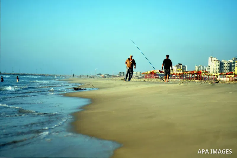 Palestinians walk at the beach on Gaza city, on August 5, 2014. Israel and Hamas began observing a temporary cease-fire on Tuesday that sets the stage for talks in Egypt on a broader deal on the Gaza Strip, including a s...