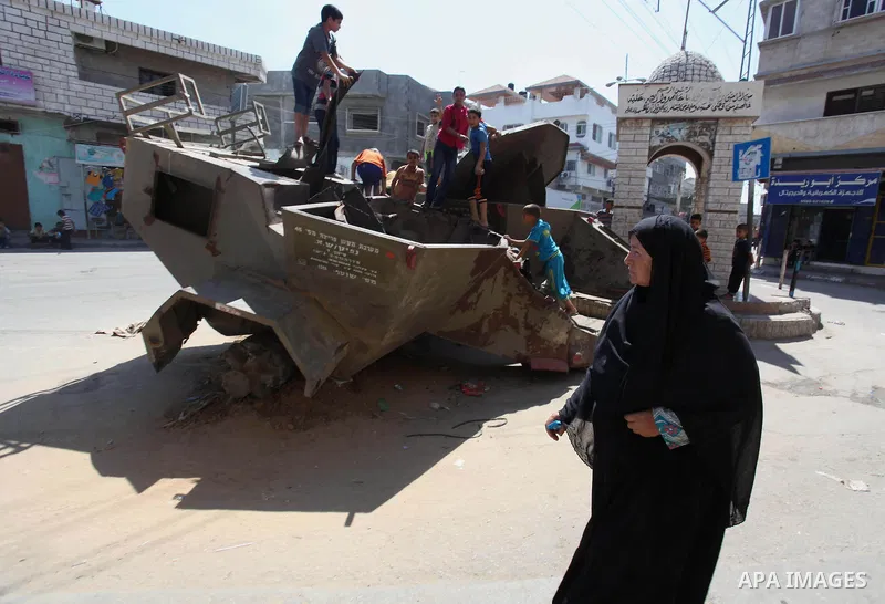 Palestinian children play on the remains of a destroyed Israeli military vehicle, in the east of Khan Younis in the southern Gaza Strip entered a second day, on August 6, 2014. while Israeli and Palestinian delegations p...