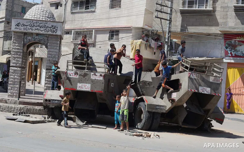 Palestinian children play on the remains of a destroyed Israeli military vehicle, in the east of Khan Younis in the southern Gaza Strip entered a second day, on August 6, 2014. while Israeli and Palestinian delegations p...