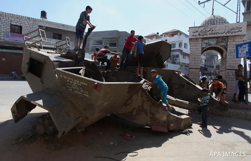 Palestinian children play on the remains of a destroyed Israeli military vehicle, in the east of Khan Younis in the southern Gaza Strip entered a second day, on August 6, 2014. while Israeli and Palestinian delegations p...