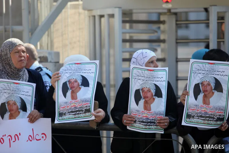 Palestinians hold signs and posters depicting Palestinian teen Mohammed Abu Khudair during a protest outside Jerusalem District Court August 6, 2014. Jerusalem District Court on Wednesday remanded Yosef Ben David, one of...
