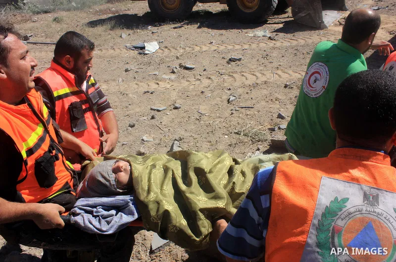 Palestinian rescue workers carry an injured woman who have been evacuated from under the rubble of a destroyed house following an Israeli air strike in Gaza city on August 08, 2014. Israel launched air strikes across the...