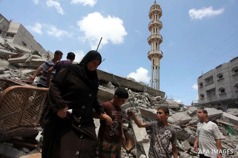 A Palestinian woman with her son walk on the rubble of al-Qassam mosque, which witnesses said was hit by an Israeli air strike, in Nuseirat refugee camp in the central Gaza Strip on August 9, 2014. Israel launched more t...