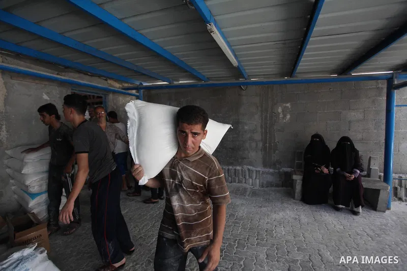 A Palestinian man carries bags of flour he received at a distribution centre of the United Nations Relief and Works Agency (UNRWA) in Gaza City on August 11, 2014. An Israeli delegation arrived in Cairo for indirect nego...