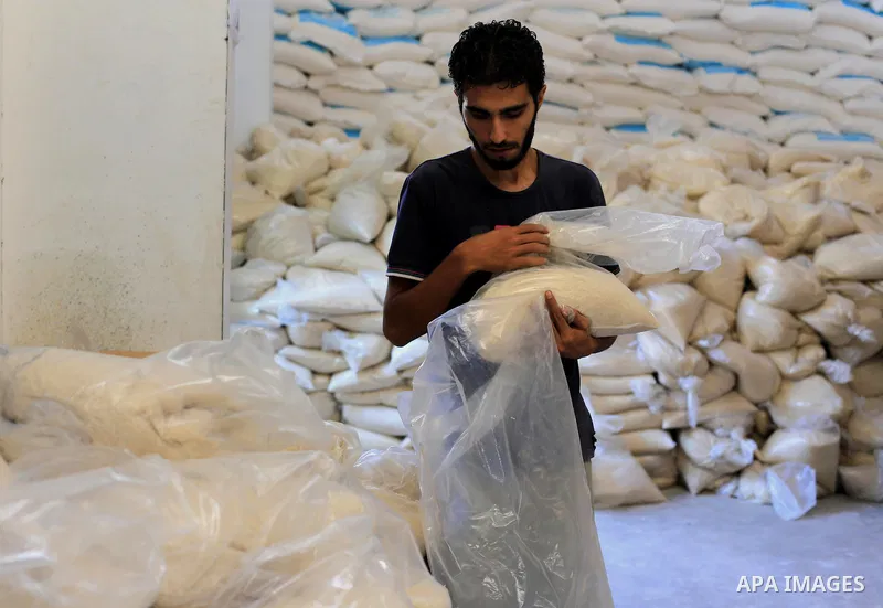 A Palestinian man carries bags of rice at a distribution centre of the United Nations Relief and Works Agency (UNRWA) in Gaza City on August 11, 2014. An Israeli delegation arrived in Cairo for indirect negotiations with...