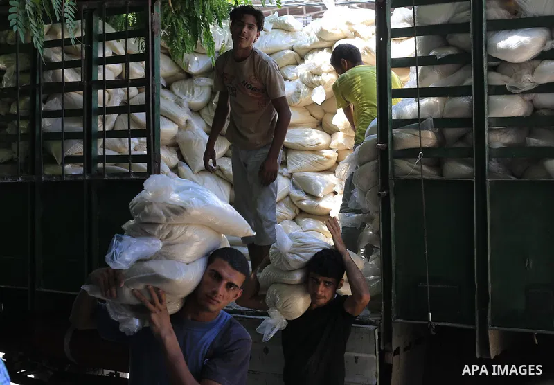 Palestinian men carry bags of rice at a distribution centre of the United Nations Relief and Works Agency (UNRWA) in Gaza City on August 11, 2014. An Israeli delegation arrived in Cairo for indirect negotiations with Pal...