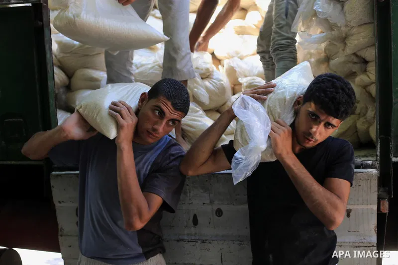 Palestinian men carry bags of rice at a distribution centre of the United Nations Relief and Works Agency (UNRWA) in Gaza City on August 11, 2014. An Israeli delegation arrived in Cairo for indirect negotiations with Pal...