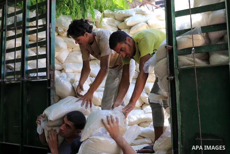 Palestinian men carry bags of rice at a distribution centre of the United Nations Relief and Works Agency (UNRWA) in Gaza City on August 11, 2014. An Israeli delegation arrived in Cairo for indirect negotiations with Pal...