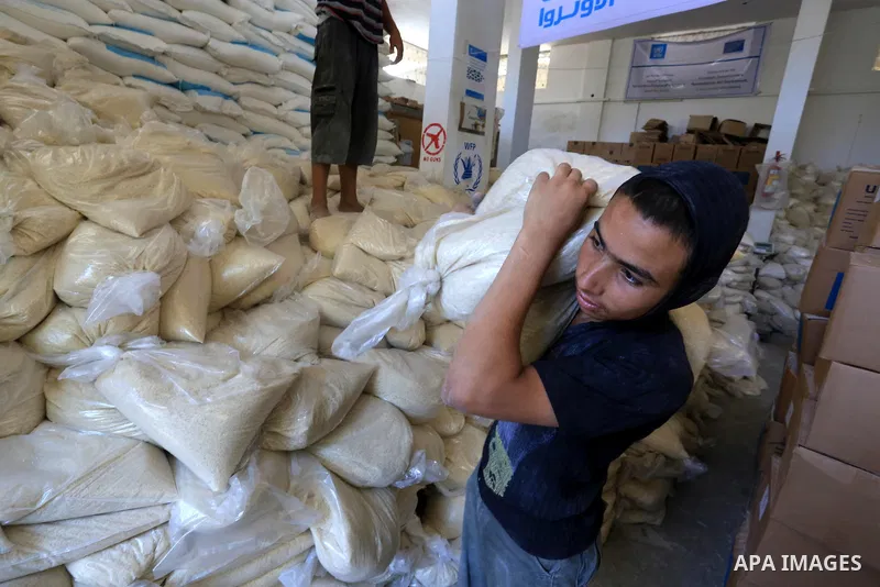 A Palestinian man carries bags of rice at a distribution centre of the United Nations Relief and Works Agency (UNRWA) in Gaza City on August 11, 2014. An Israeli delegation arrived in Cairo for indirect negotiations with...