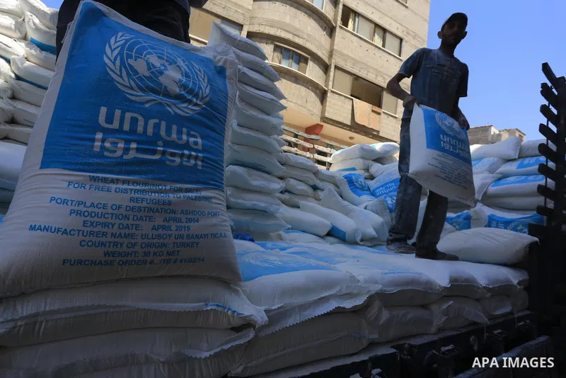 A Palestinian man carries bags of flour he received at a distribution centre of the United Nations Relief and Works Agency (UNRWA) in Gaza City on August 11, 2014. An Israeli delegation arrived in Cairo for indirect nego...
