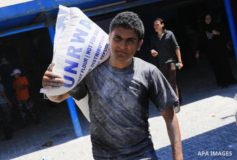 A Palestinian man carries bags of flour he received at a distribution centre of the United Nations Relief and Works Agency (UNRWA) in Gaza City on August 11, 2014. An Israeli delegation arrived in Cairo for indirect nego...