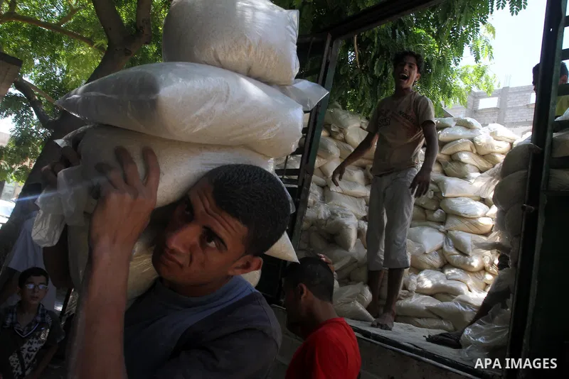 A Palestinian man carries bags of rice at a distribution centre of the United Nations Relief and Works Agency (UNRWA) in Gaza City on August 11, 2014. An Israeli delegation arrived in Cairo for indirect negotiations with...