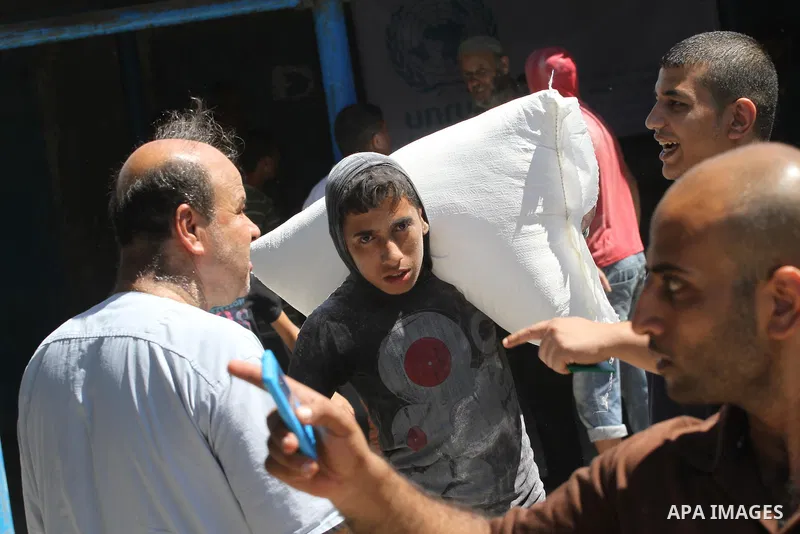 A Palestinian man carries bags of flour he received at a distribution centre of the United Nations Relief and Works Agency (UNRWA) in Gaza City on August 11, 2014. An Israeli delegation arrived in Cairo for indirect nego...