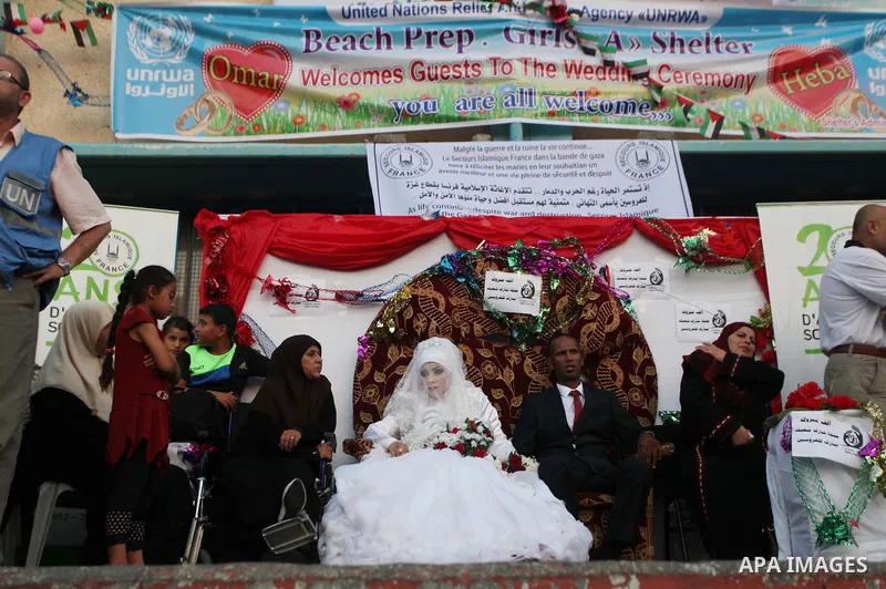 A Palestinian couple celebrate their wedding ceremony at a United Nations-run school sheltering displaced Palestinians from the Israeli offensive, in Shati refugee camp in Gaza City August 13, 2014. The threat of renewed...