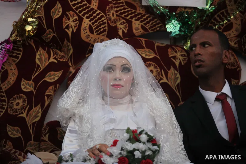 A Palestinian couple celebrate their wedding ceremony at a United Nations-run school sheltering displaced Palestinians from the Israeli offensive, in Shati refugee camp in Gaza City August 13, 2014. The threat of renewed...