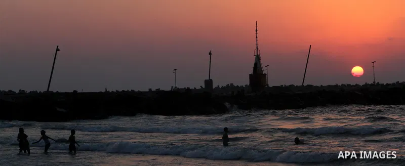 Palestinians take a dip in the sea as the sun sets over the Gaza City, on August 14, 2014.A fresh five-day ceasefire between Palestinian militants and Israel went into force early Thursday, agreed at the end of a three-d...