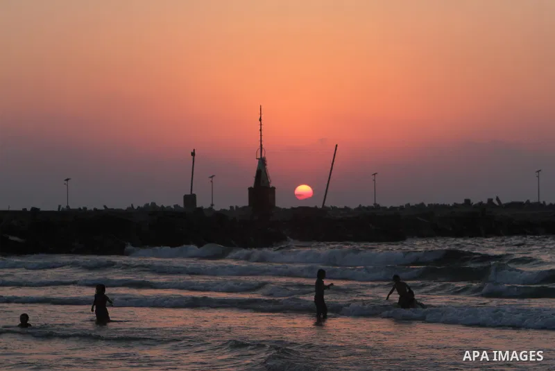 Palestinians take a dip in the sea as the sun sets over the Gaza City, on August 14, 2014.A fresh five-day ceasefire between Palestinian militants and Israel went into force early Thursday, agreed at the end of a three-d...