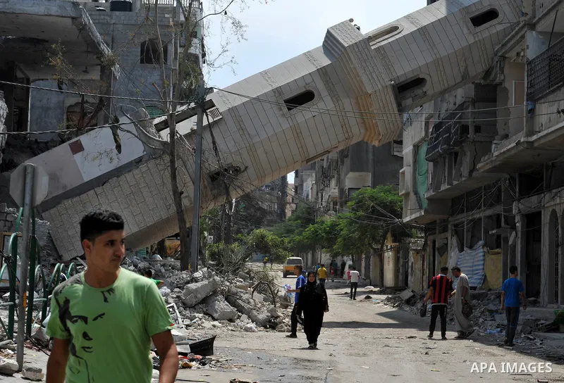 Palestinians walk past a mosque which witnesses said was destroyed by an Israel air strike during the offensive, on the second day of a five-day ceasefire, in Gaza city on August 15, 2014. Israel and Palestinians are obs...