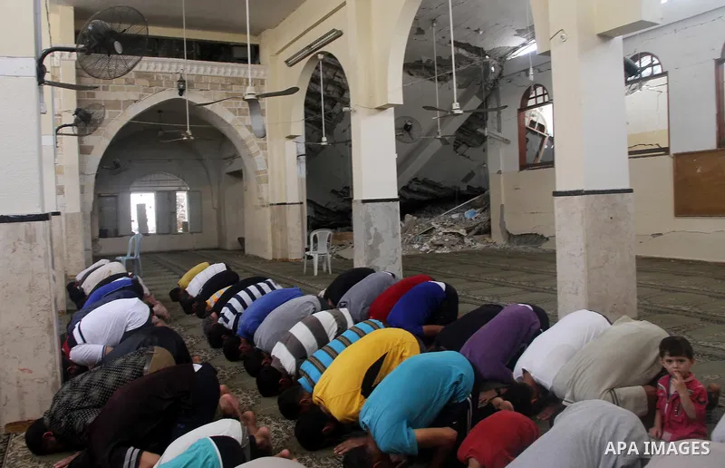 Palestinian worshipers perform Friday prayers next to the remains of a mosque which witnesses said was destroyed by an Israel air strike during the offensive, on the second day of a five-day ceasefire in Gaza City August...
