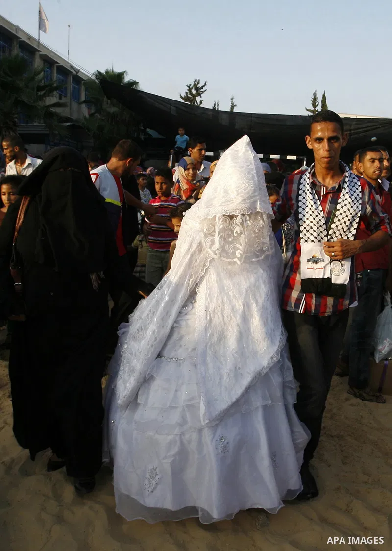 A Palestinian bride and her groom, who each lost his home during fighting between Hamas and Israel, pose for a picture during their wedding ceremony, along with two other couples, at a UN school in Rafah in southern Gaza...