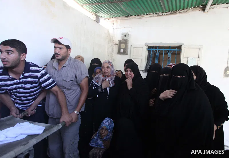 Palestinian relatives mourn on the bodies of members of the Alouh family, killed in an Israeli airstrike during their funeral in Deir al-Balah in the center of the Gaza Strip, on August 20, 2014. An Israeli air strike on...