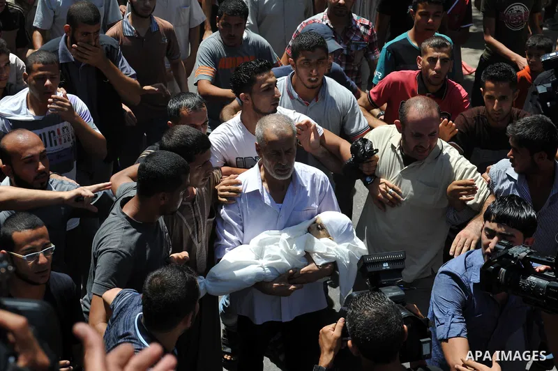 A relative of the wife of Hamas's military leader, Mohammed Deif, and his infant son Ali, whom medics said were killed in Israeli air strikes, carries Ali's body during their funeral in the northern Gaza Strip August 20,...