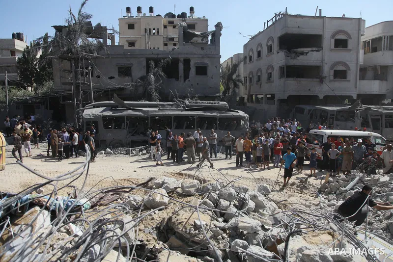 Palestinians stand in front of a bus that witnesses said was destroyed during an Israeli airstrike in Gaza City August 20, 2014. Hamas militants in the Gaza Strip fired rockets at Israel for a second day on Wednesday aft...