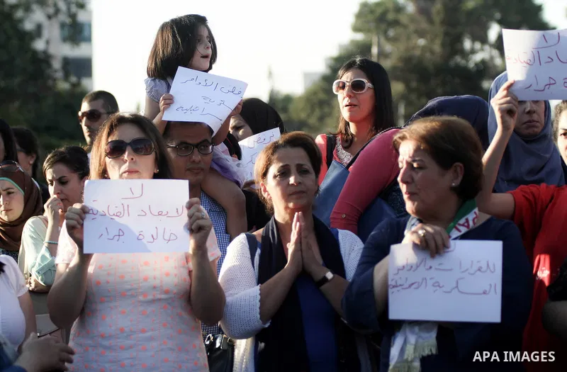 Palestinians hold up signs as they take part in a rally outside the United Nations offices in the West Bank city of Ramallah on August 18, 2014. Photo by Shadi Hatem