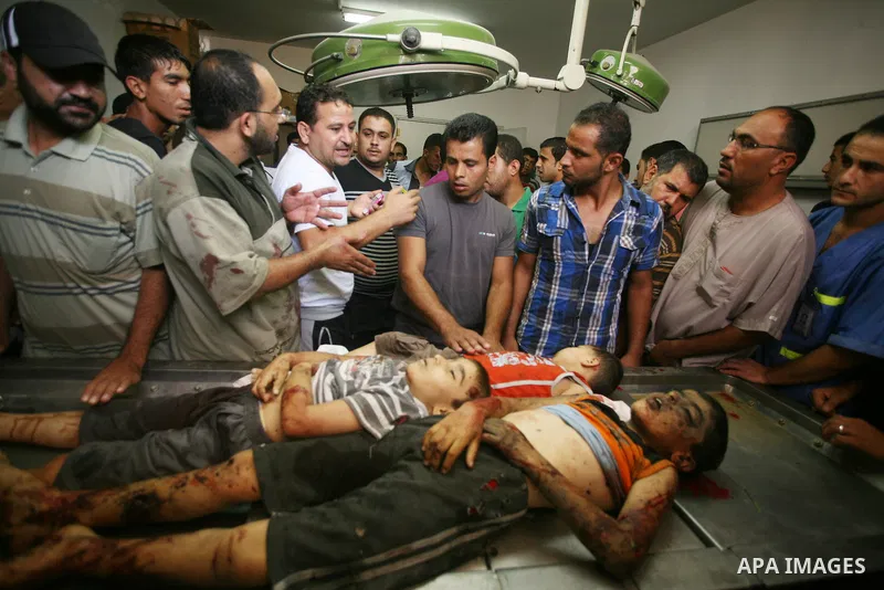 Palestinians gather around the bodies of three children from the Al-Rifi family upon their arrival at Gaza city's Al-Shifa hospital on August 21, 2014. Three senior Hamas commanders and four children were among at least...