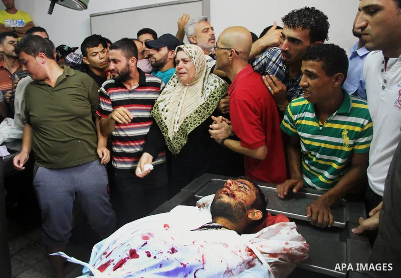 Palestinians mourn over the body of his relative Rami Abu Nahel, killed in an Israeli military strike, at Gaza city's Al-Shifa hospital on August 21, 2014. Three senior Hamas commanders and four children were among at le...