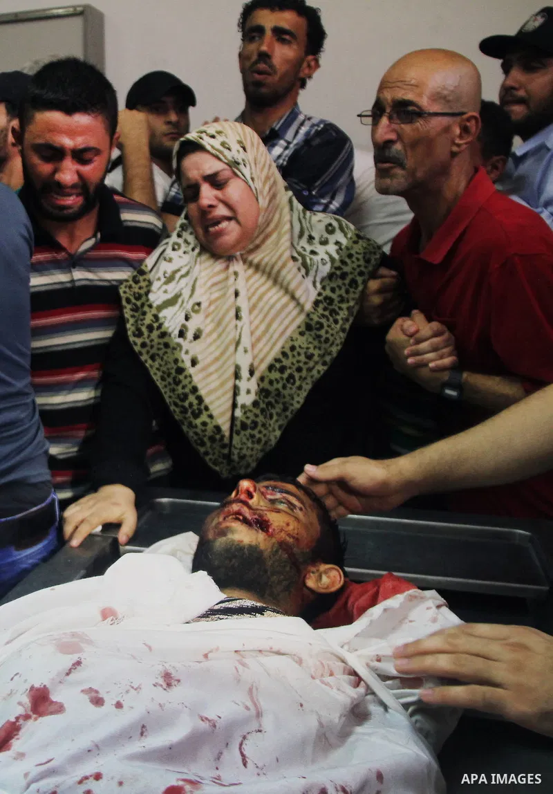 Palestinians mourn over the body of his relative Rami Abu Nahel, killed in an Israeli military strike, at Gaza city's Al-Shifa hospital on August 21, 2014. Three senior Hamas commanders and four children were among at le...
