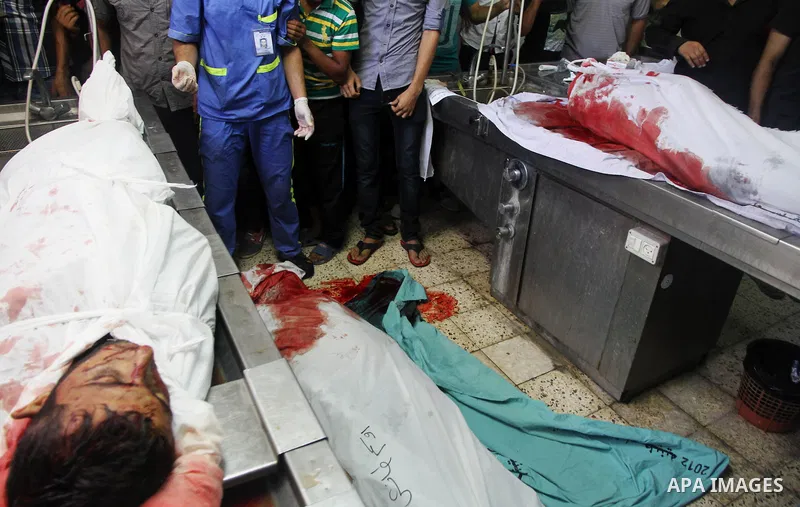 Palestinians gather around the bodies of Palestinian men upon their arrival at Gaza city's Al-Shifa hospital on August 21, 2014. Three senior Hamas commanders and four children were among at least 15 Palestinians killed...