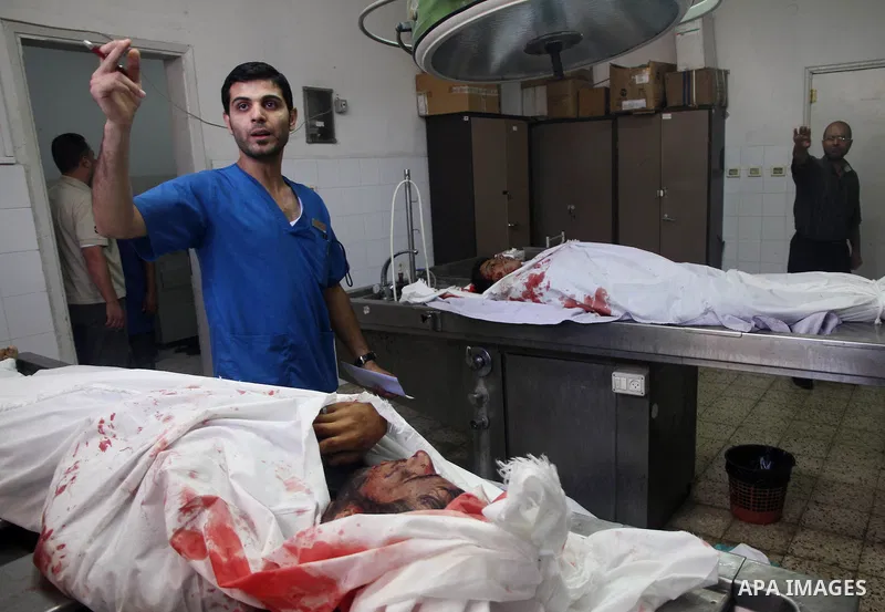 Palestinians gather around the bodies of Palestinian men upon their arrival at Gaza city's Al-Shifa hospital on August 21, 2014. Three senior Hamas commanders and four children were among at least 15 Palestinians killed...