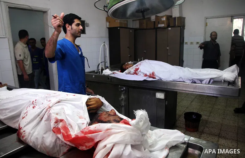 Palestinians gather around the bodies of Palestinian men upon their arrival at Gaza city's Al-Shifa hospital on August 21, 2014. Three senior Hamas commanders and four children were among at least 15 Palestinians killed...