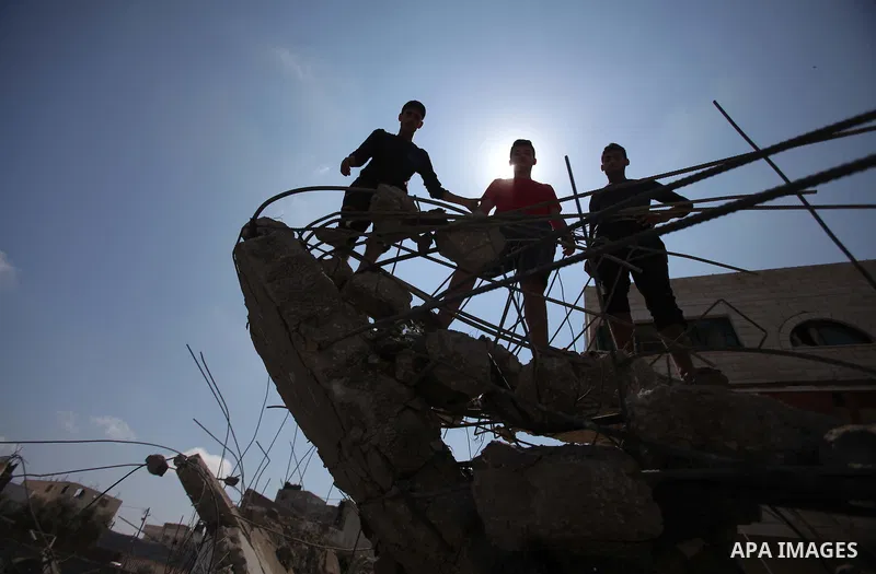 Palestinians gather around the remains of a house, which witnesses said was destroyed in an Israeli air strike, in Gaza City August 22, 2014. Since the collapse on Tuesday of a 10-day ceasefire, the Israeli military has...